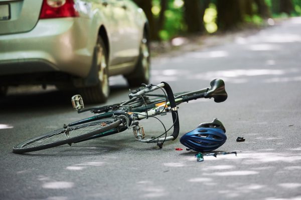 No people. Bicycle and silver colored car accident on the road at forest at daytime